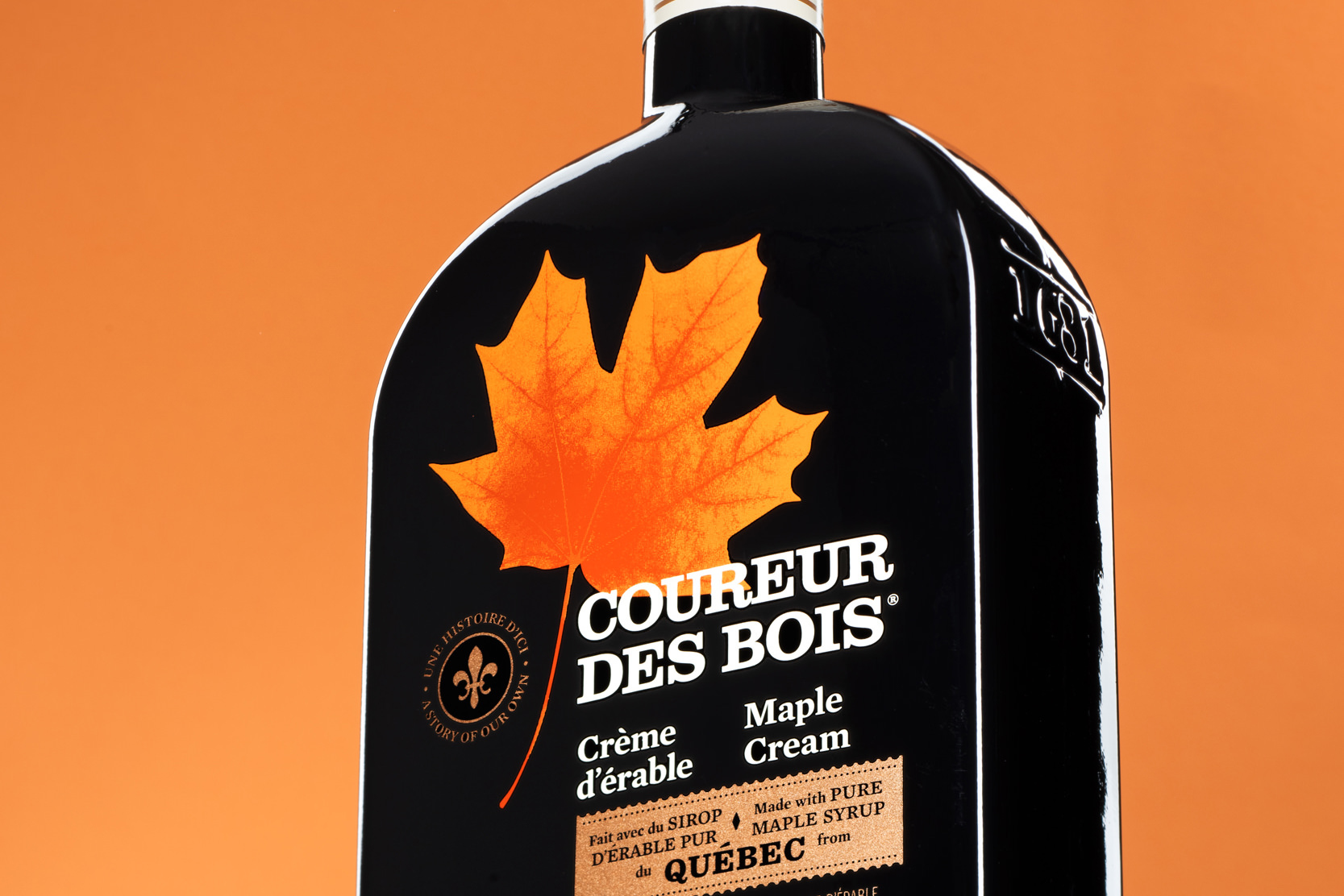 Bouteille Coureur des Bois posée sur une tablette en verre avec fond orange