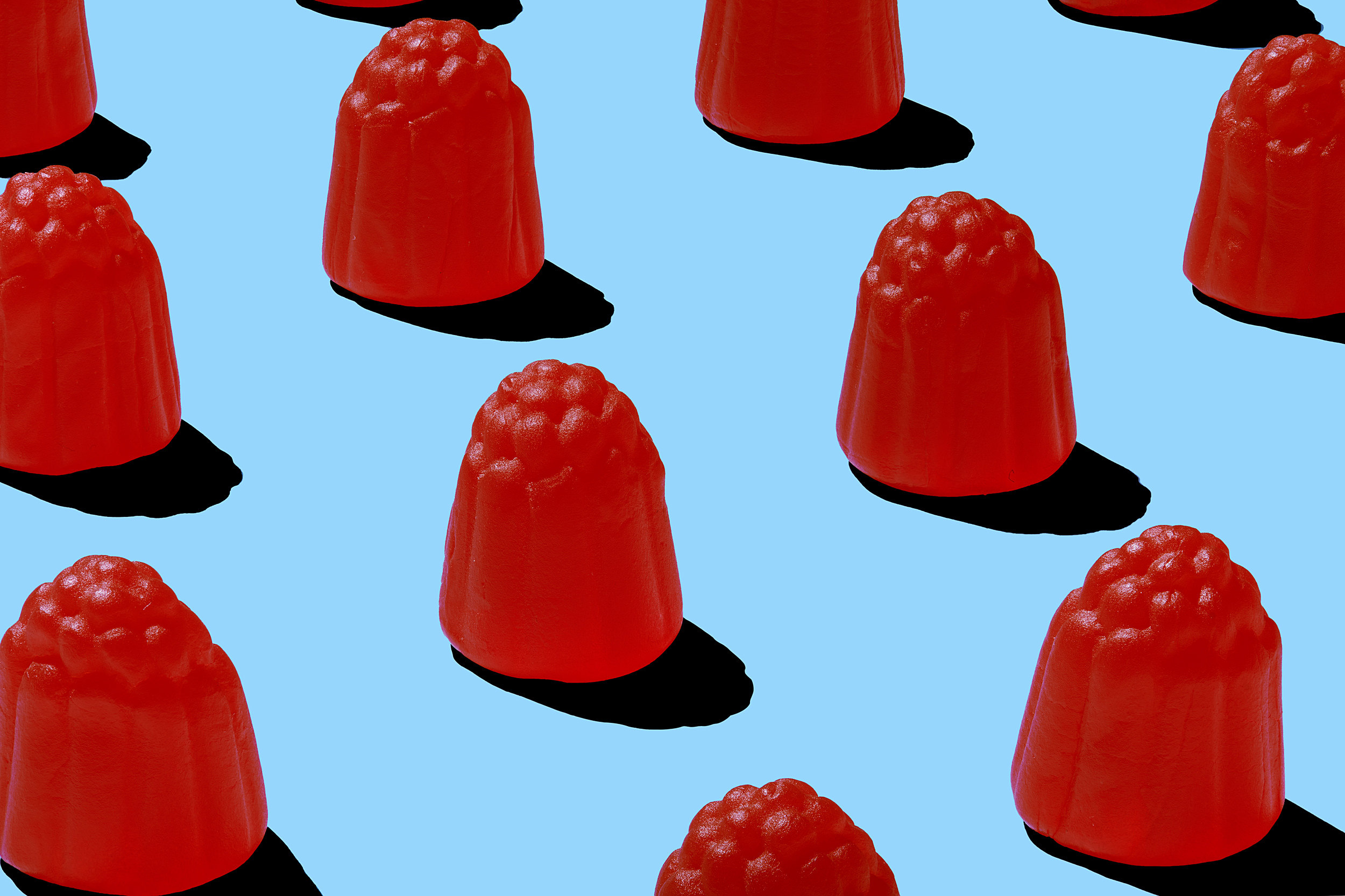 Bright red raspberry candy lined up on a flat blue surface